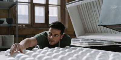 A man inspects ceramic pieces outside the high-temperature kiln to showcase advanced ceramic engineering success.