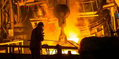 Man working at a foundry with steam and molten metal depicting the investment casting process.