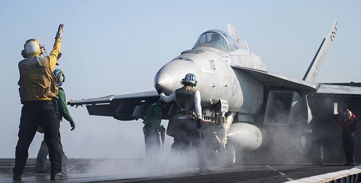 Crew guides fighter jet landing on aircraft carrier